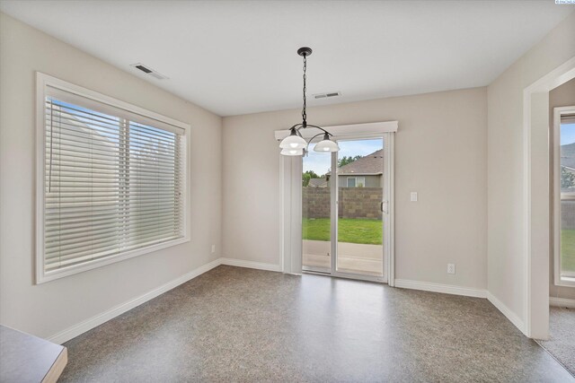 spare room featuring a chandelier and baseboards