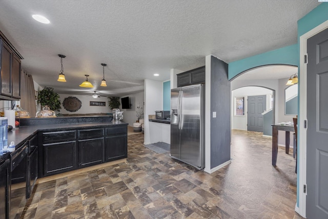 6115 Wildcat Ln, Pasco, WA 99301 - kitchen featuring a peninsula, arched walkways, stainless steel fridge, a textured ceiling, and dark countertops