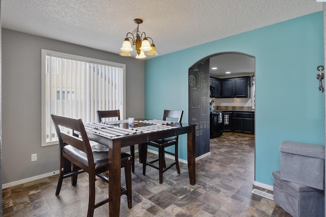 6115 Wildcat Ln, Pasco, WA 99301 - dining room featuring arched walkways, stone finish flooring, baseboards, and an inviting chandelier