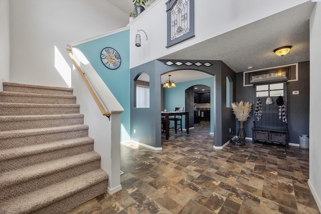 6115 Wildcat Ln, Pasco, WA 99301 - staircase with arched walkways, stone finish floor, a high ceiling, and baseboards