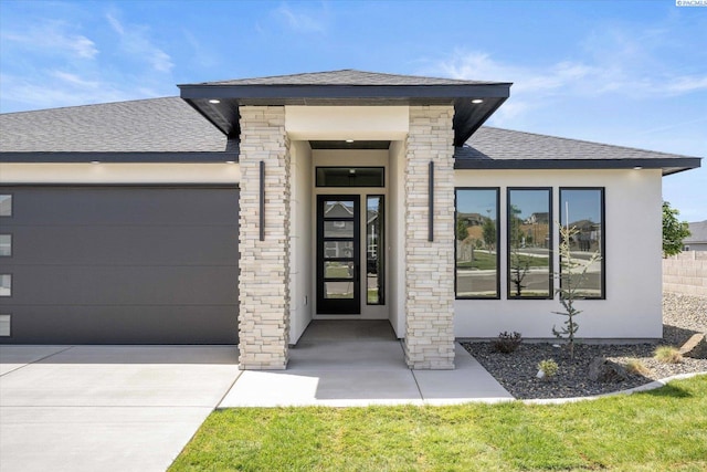 561 Lazio Way, Richland, WA 99352 - property entrance with a shingled roof, a garage, concrete driveway, and stucco siding
