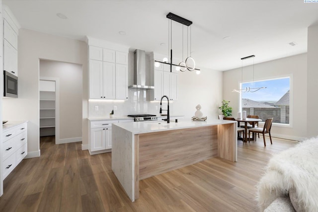 561 Lazio Way, Richland, WA 99352 - kitchen with wall chimney exhaust hood, a chandelier, a sink, light wood-type flooring, and light countertops