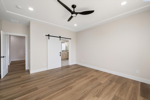 561 Lazio Way, Richland, WA 99352 - unfurnished bedroom with a barn door, light wood-type flooring, baseboards, recessed lighting, and ceiling fan