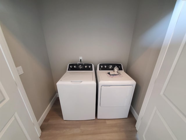clothes washing area featuring baseboards, washer and dryer, laundry area, and light wood-style flooring