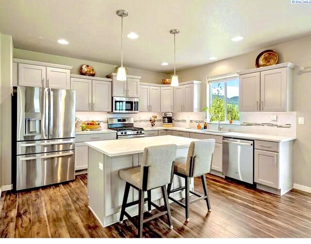 2855 S Dawes Pl, Kennewick, WA 99338 - kitchen featuring decorative backsplash, a kitchen bar, a center island, dark wood-type flooring, and appliances with stainless steel finishes