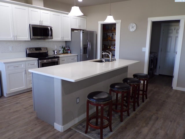 166214 W Johnson Rd, Prosser, WA 99350 - kitchen featuring appliances with stainless steel finishes, white cabinetry, a center island with sink, and dark wood-style floors