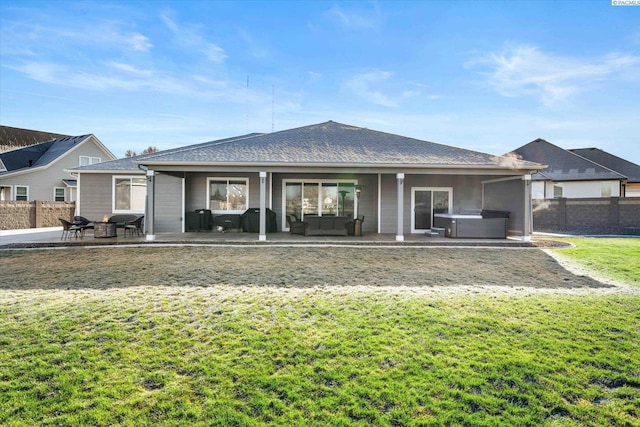 rear view of house with an outdoor hangout area, a yard, a patio area, and a hot tub