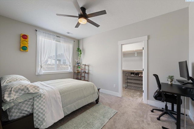 carpeted bedroom featuring a walk in closet, a closet, and ceiling fan