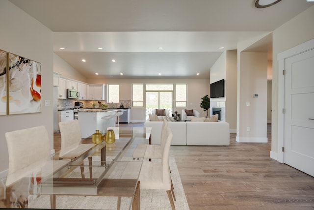 dining space featuring sink, vaulted ceiling, and light wood-type flooring