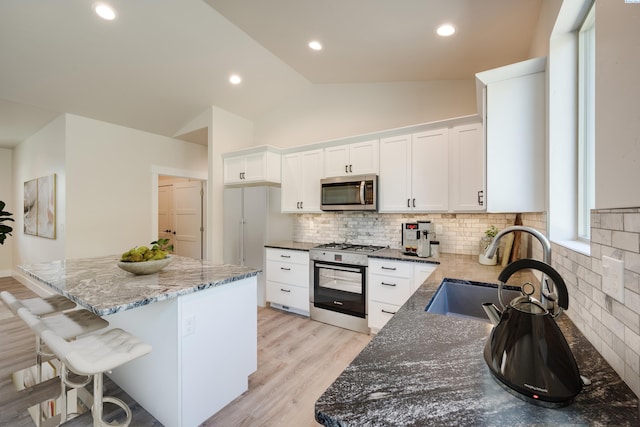 kitchen featuring sink, white cabinetry, dark stone countertops, a kitchen island, and stainless steel appliances