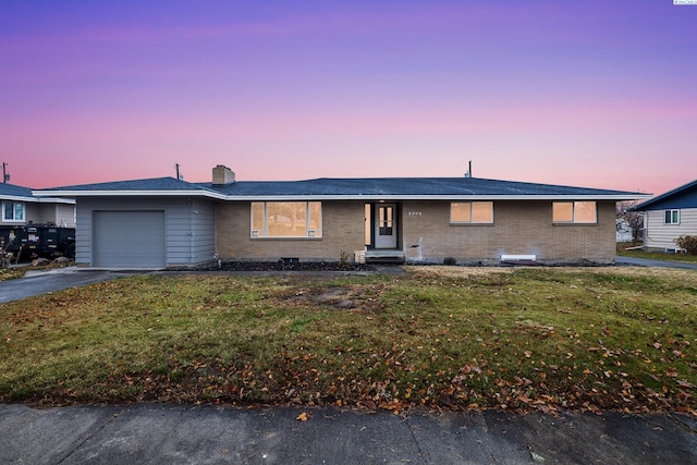 ranch-style house with a garage and a lawn