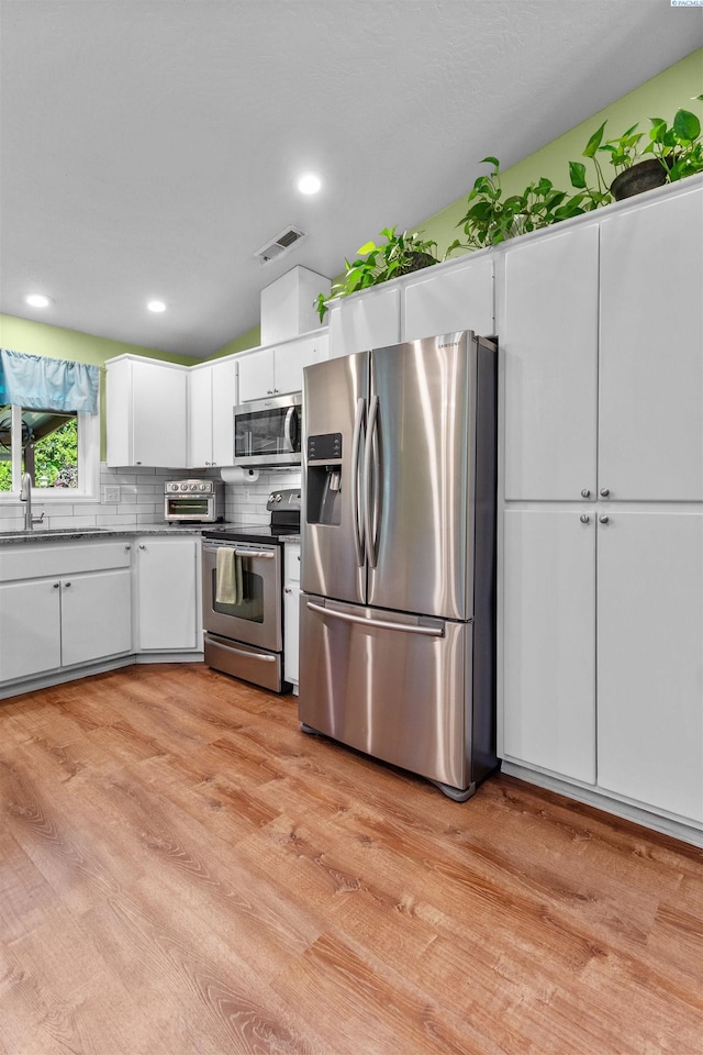 4500 S Dayton Ct, Kennewick, WA 99337 - kitchen with stainless steel appliances, light wood-style floors, white cabinets, a sink, and backsplash