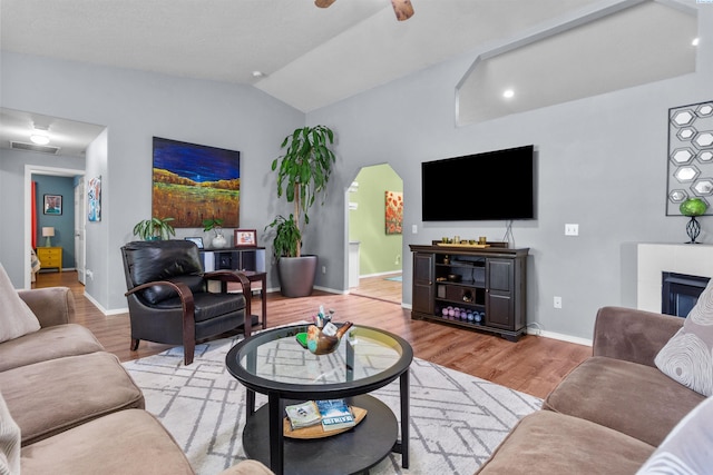 4500 S Dayton Ct, Kennewick, WA 99337 - living room featuring vaulted ceiling, light wood-type flooring, baseboards, a ceiling fan, and a tiled fireplace