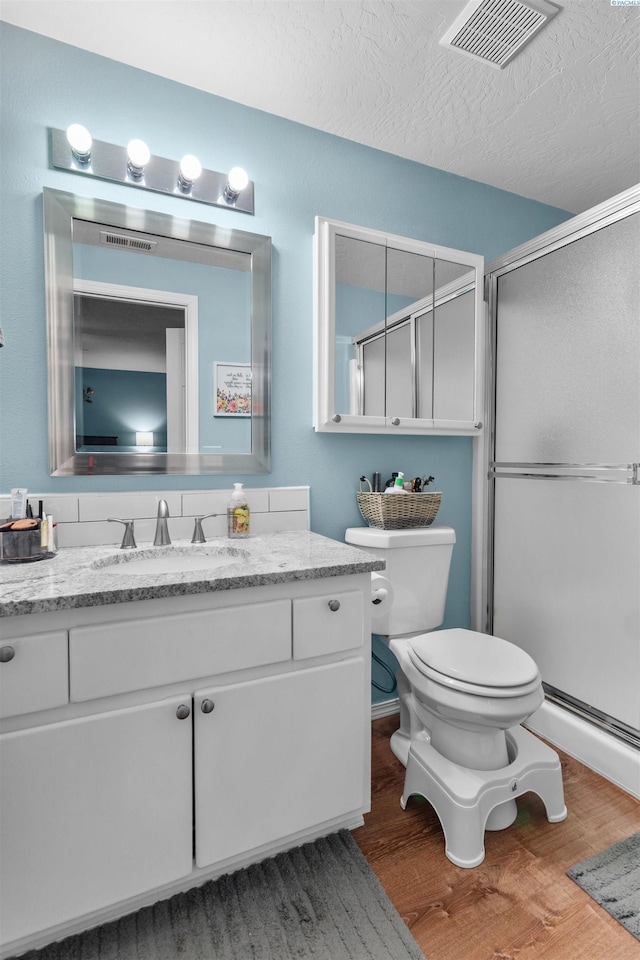 4500 S Dayton Ct, Kennewick, WA 99337 - full bath with wood finished floors, toilet, a stall shower, vanity, and a textured ceiling