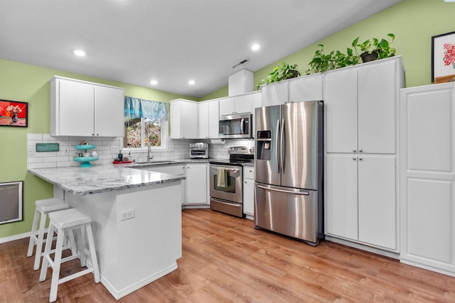 4500 S Dayton Ct, Kennewick, WA 99337 - kitchen with stainless steel appliances, a peninsula, tasteful backsplash, white cabinets, and vaulted ceiling