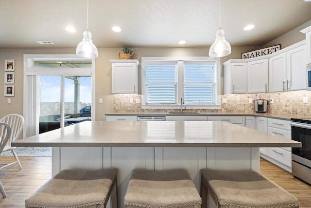 3011 S Dawes Pl, Kennewick, WA 99338 - kitchen with a sink, a breakfast bar area, light wood finished floors, white cabinetry, and decorative backsplash