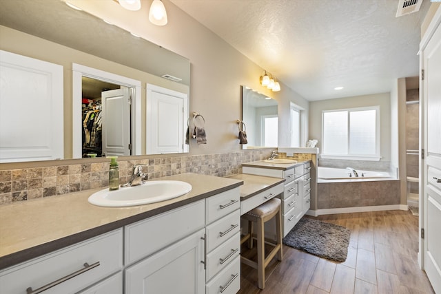 3011 S Dawes Pl, Kennewick, WA 99338 - full bath featuring vanity, a bath, wood finished floors, a spacious closet, and a textured ceiling