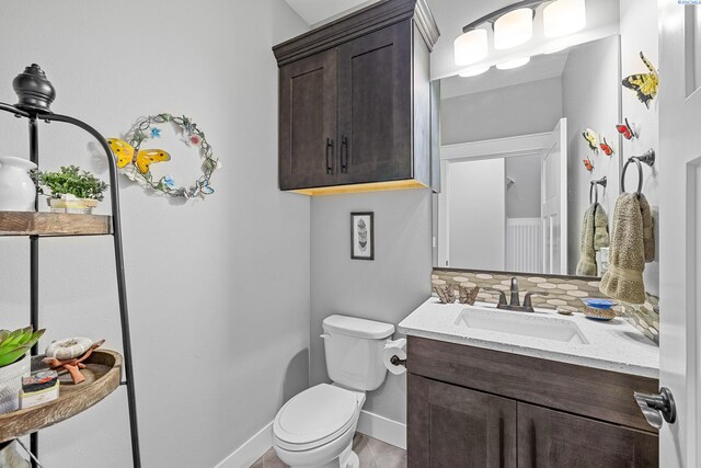 bathroom featuring toilet, baseboards, and vanity