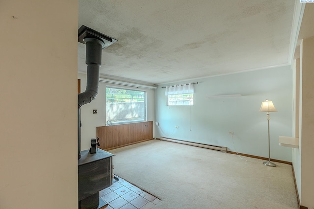 unfurnished living room with baseboard heating, a wood stove, light carpet, and a textured ceiling