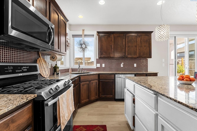 6013 Somerset Ln, Pasco, WA 99301 - kitchen featuring stainless steel appliances, a sink, light wood-type flooring, light stone counters, and decorative backsplash