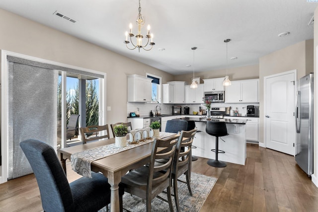 dining space with a notable chandelier, visible vents, and dark wood-style flooring