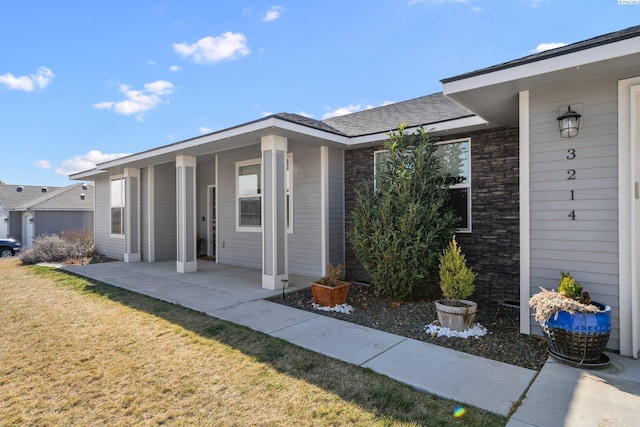 view of exterior entry featuring stone siding and a lawn