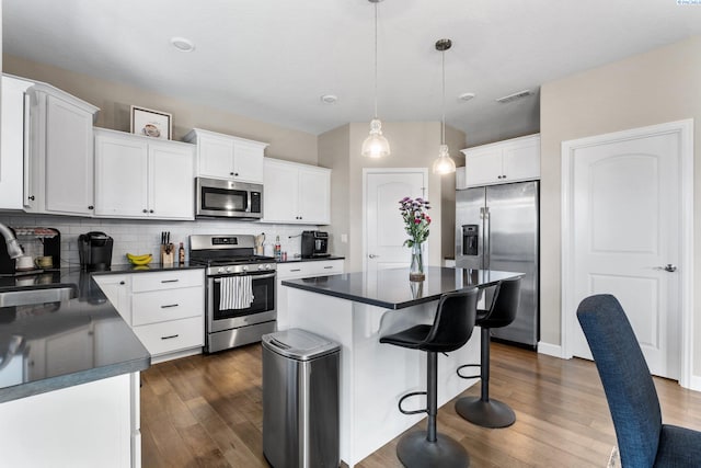 kitchen with a sink, stainless steel appliances, dark countertops, and backsplash