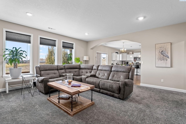 living area featuring arched walkways, visible vents, a textured ceiling, and baseboards