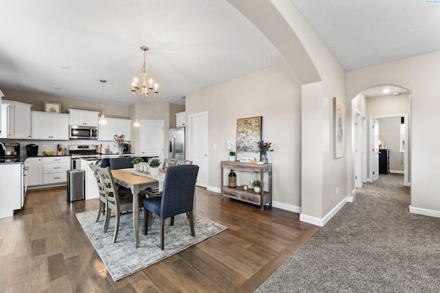 dining area with arched walkways, dark wood finished floors, an inviting chandelier, and baseboards