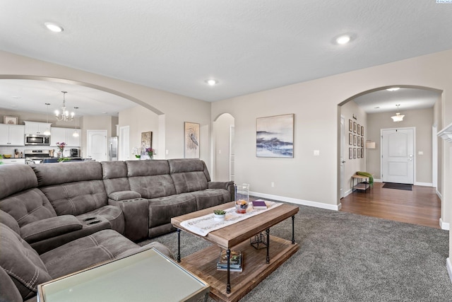 living area featuring dark colored carpet, baseboards, an inviting chandelier, and recessed lighting