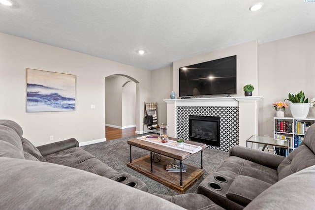 living area featuring recessed lighting, a fireplace, arched walkways, and baseboards