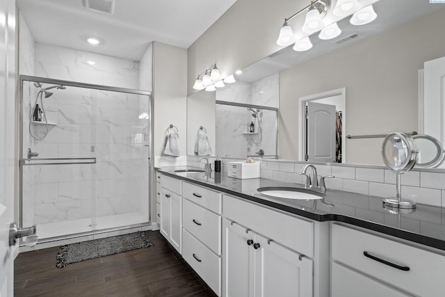 full bathroom with a sink, visible vents, a marble finish shower, and wood finished floors