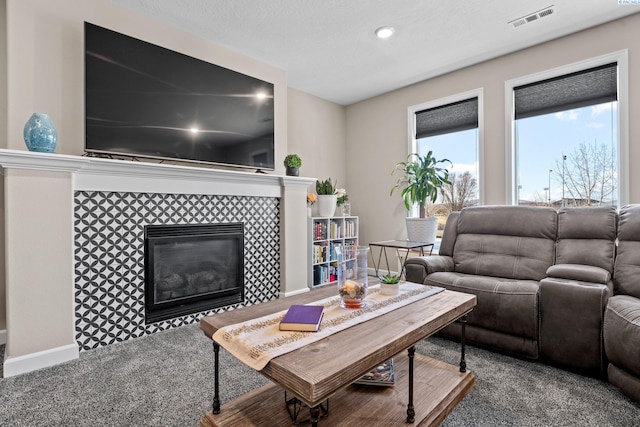 living room featuring carpet flooring, a fireplace, visible vents, and baseboards