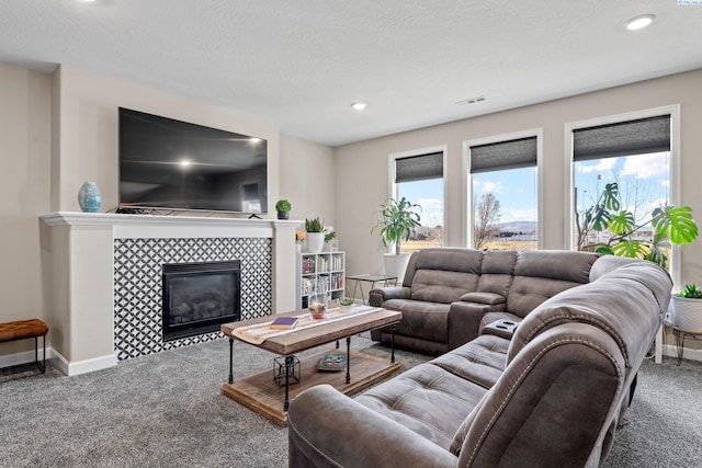 carpeted living room featuring visible vents, baseboards, recessed lighting, a tile fireplace, and a textured ceiling