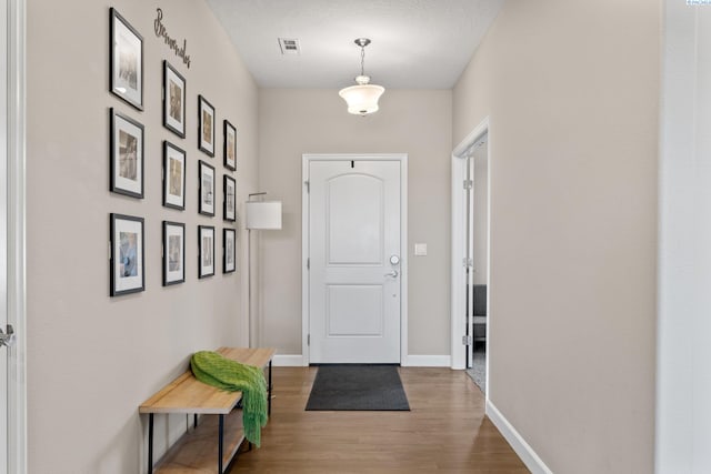 entryway featuring visible vents, baseboards, and wood finished floors