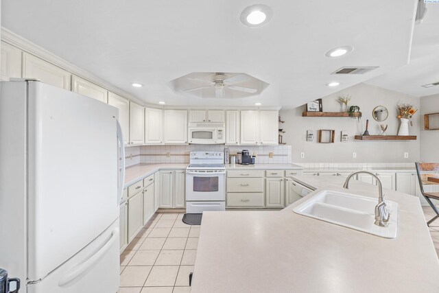 kitchen featuring light tile patterned flooring, sink, a tray ceiling, white appliances, and backsplash