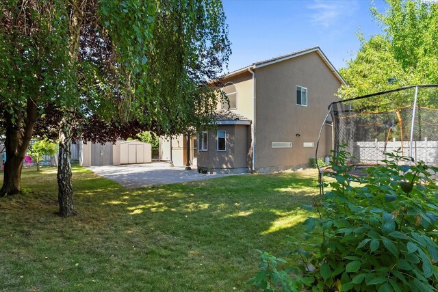 5405 Warbler Ln, West Richland, WA 99353 - view of home's exterior featuring a yard, stucco siding, a trampoline, an outdoor structure, and a patio area