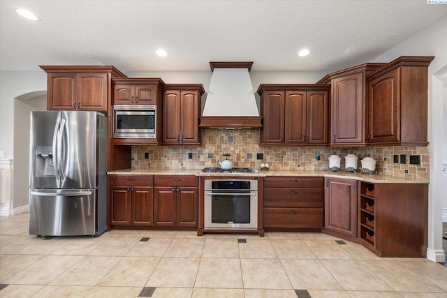 1010 Christopher Ln, Pasco, WA 99301 - kitchen with stainless steel appliances, custom exhaust hood, decorative backsplash, light stone counters, and a textured ceiling