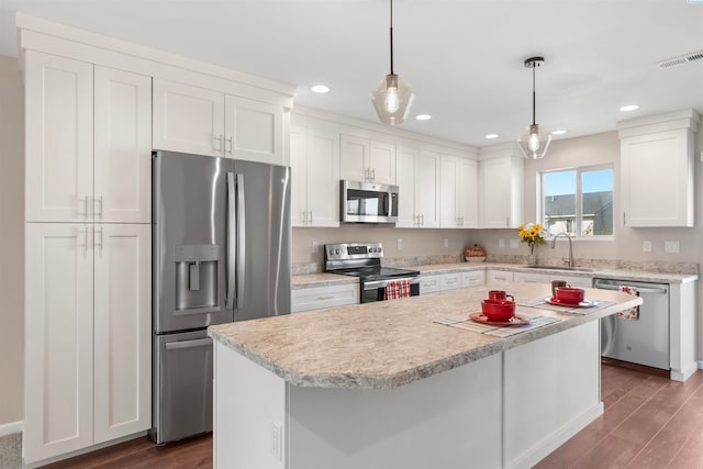 kitchen featuring white cabinetry, sink, stainless steel appliances, and a center island