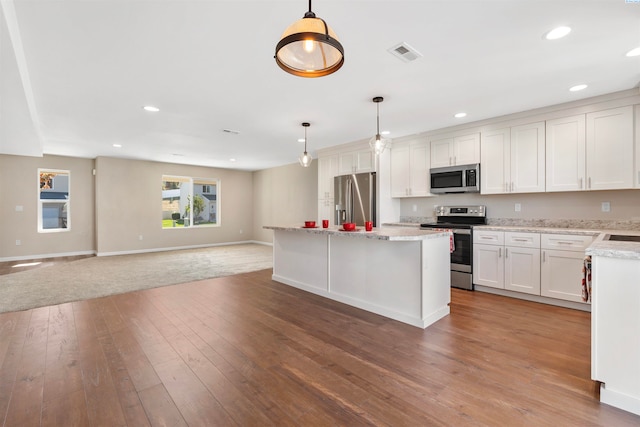 kitchen with white cabinetry, hardwood / wood-style floors, stainless steel appliances, a center island, and decorative light fixtures