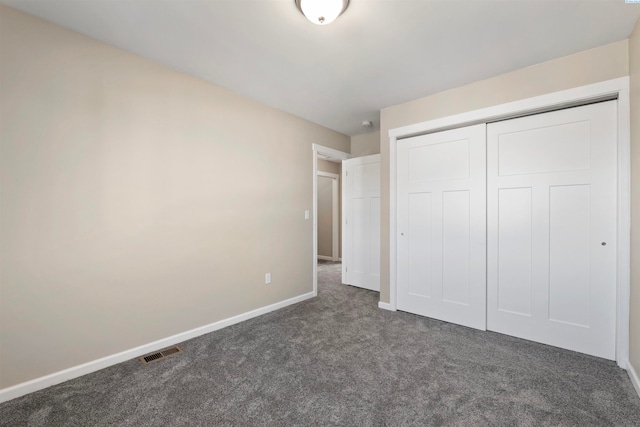 unfurnished bedroom featuring dark carpet and a closet