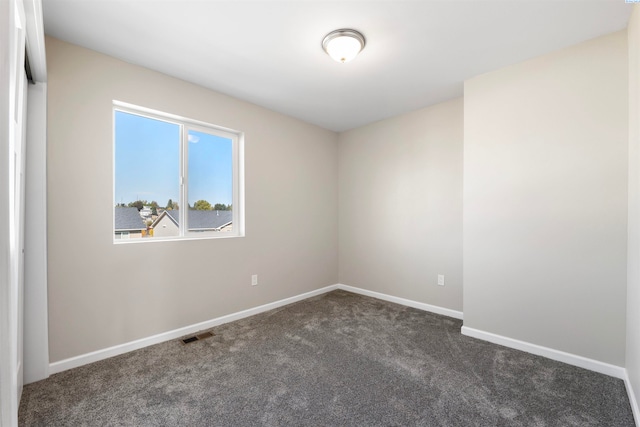 spare room featuring dark carpet