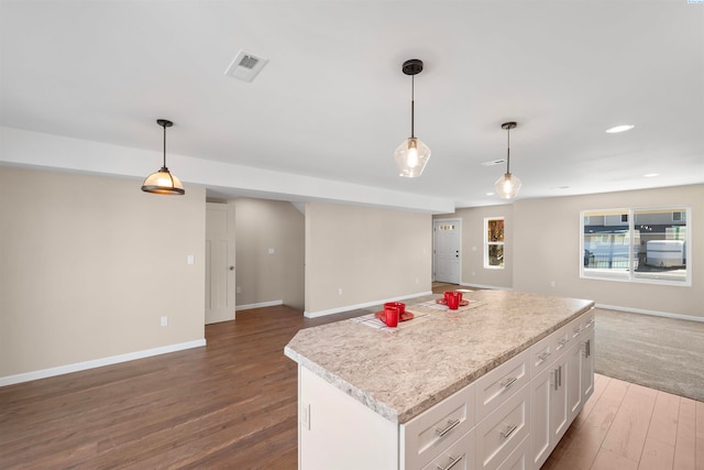 kitchen featuring pendant lighting, dark hardwood / wood-style floors, a kitchen island, and white cabinets