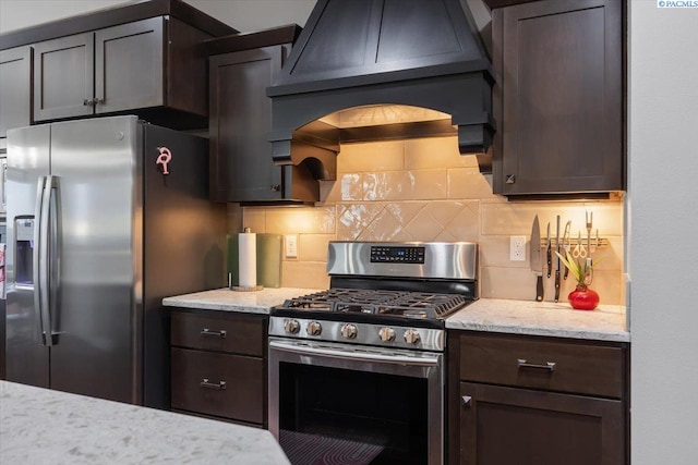 5298 S Quincy Pl, Kennewick, WA 99337 - kitchen with custom range hood, light stone counters, backsplash, dark brown cabinets, and stainless steel appliances