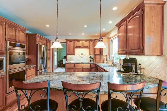 3114 Rd 103, Pasco, WA 99301 - kitchen featuring tasteful backsplash, a peninsula, a breakfast bar, appliances with stainless steel finishes, and a sink