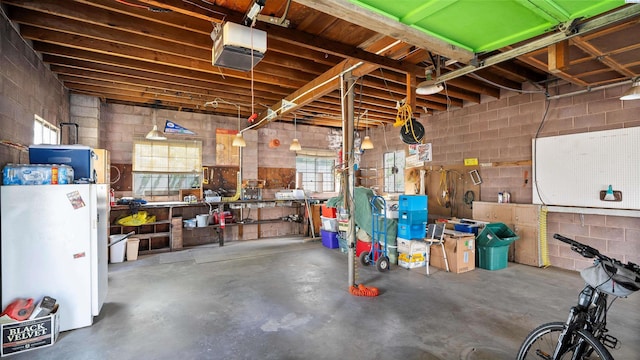 1707 W 19th Ave, Kennewick, WA 99337 - garage featuring a garage door opener, freestanding refrigerator, and concrete block wall