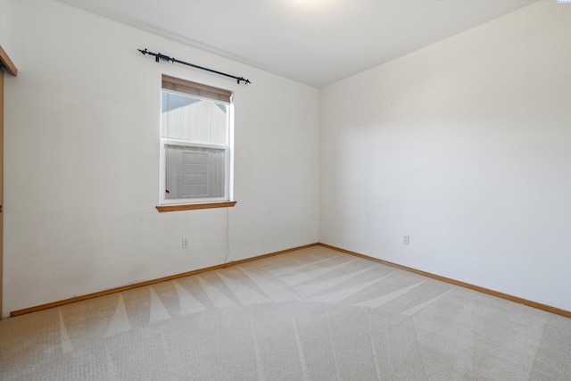 unfurnished room with light carpet and baseboards