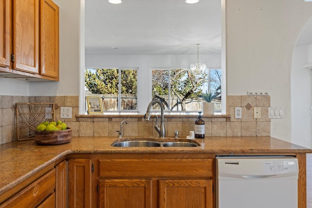 kitchen featuring plenty of natural light, white dishwasher, a sink, and brown cabinets