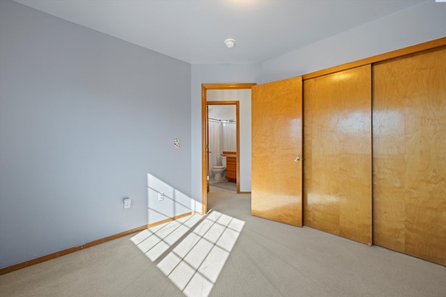 unfurnished bedroom with light carpet, baseboards, and a closet