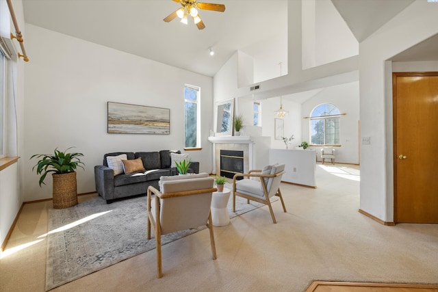 living room featuring a fireplace, light colored carpet, visible vents, a ceiling fan, and high vaulted ceiling